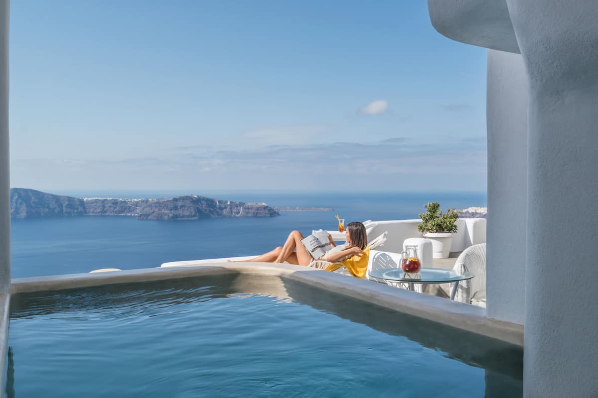 A person relaxing by a pool with a view of the sea and a distant coastline.