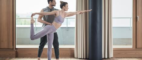 Una habitación con ventanas amplias, suelo de madera y una esterilla de yoga.