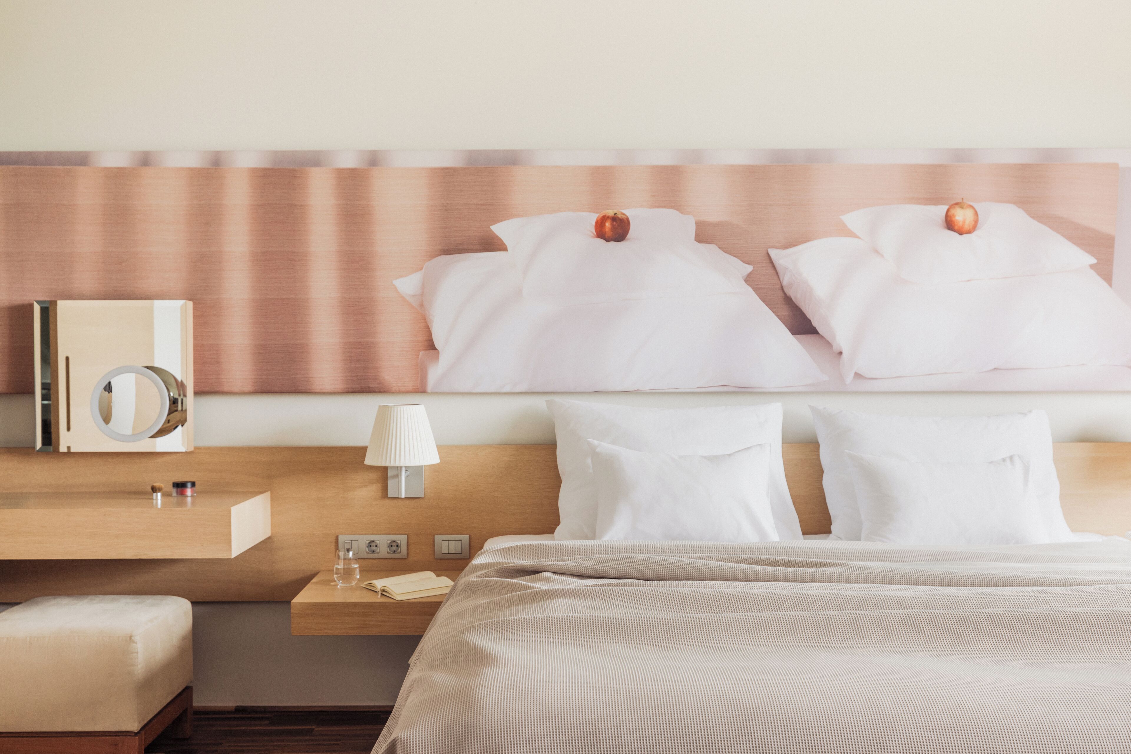 Una habitación de hotel con cama, mesita de noche, lámpara y espejo.