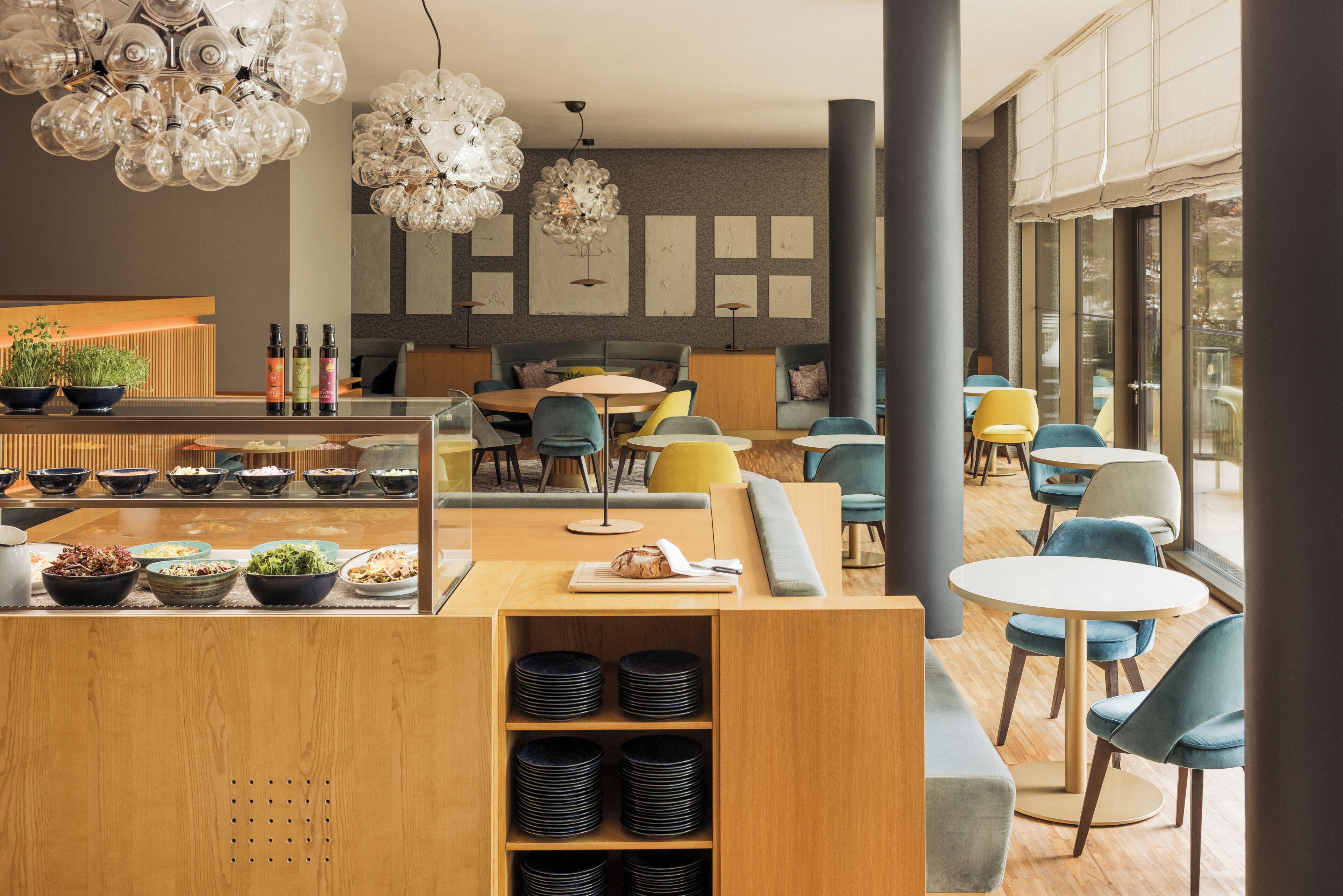 A modern restaurant interior with a central counter, seating area, and decorative lighting.