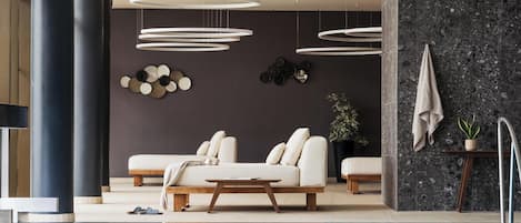 Un interior moderno con piscina, un conjunto de sofás y una pared oscura decorada con placas.