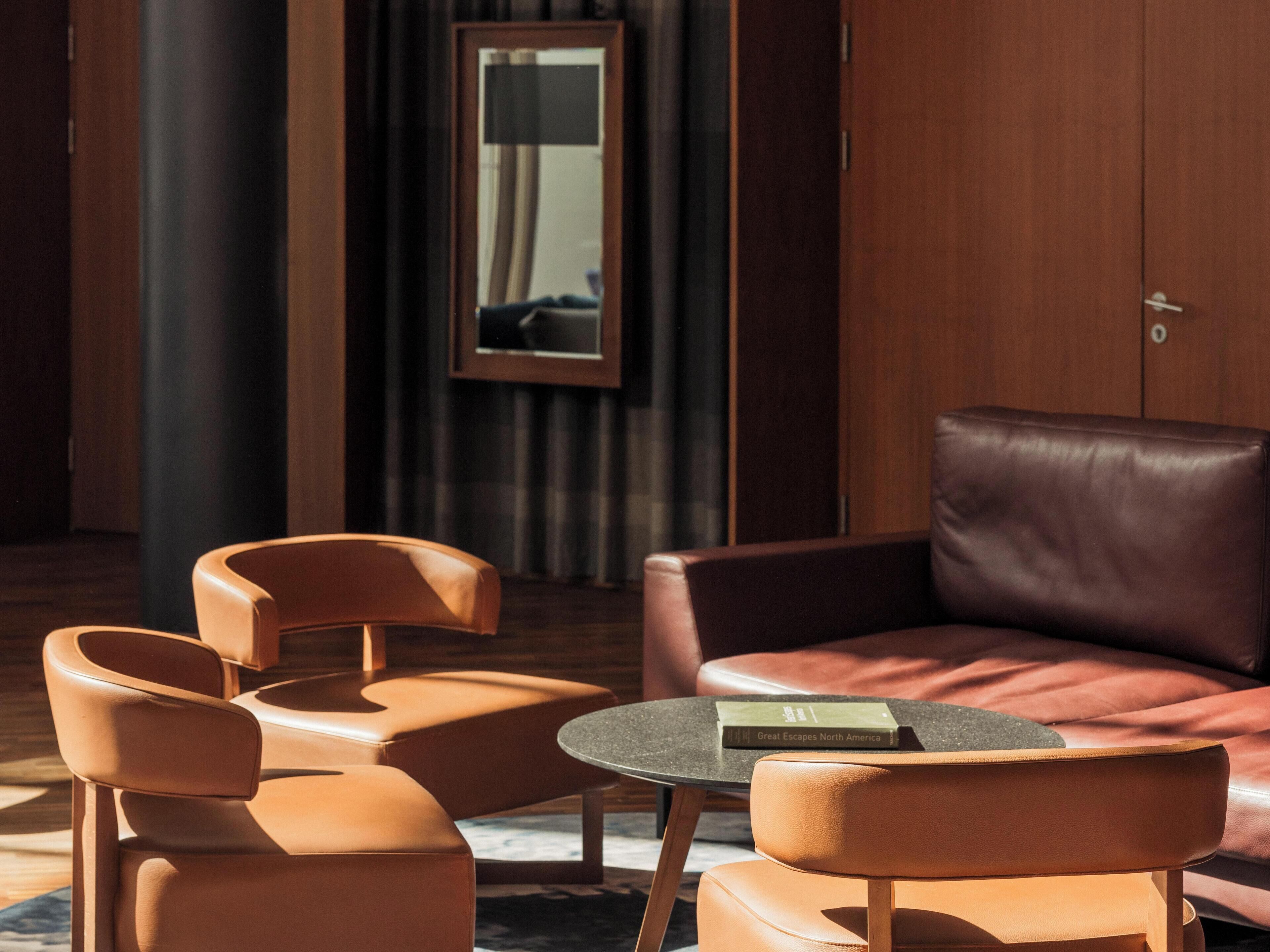 Una habitación moderna con muebles de cuero, una mesa redonda y un espejo enmarcado.