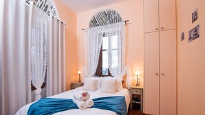 Ein Schlafzimmer mit einem Bett, zwei Nachttischen, einem Kleiderschrank und einem Fenster mit Vorhang.