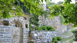 Ein Steinweg führt zu einem Steinhaus mit einem kleinen Rundbogenbogen.
