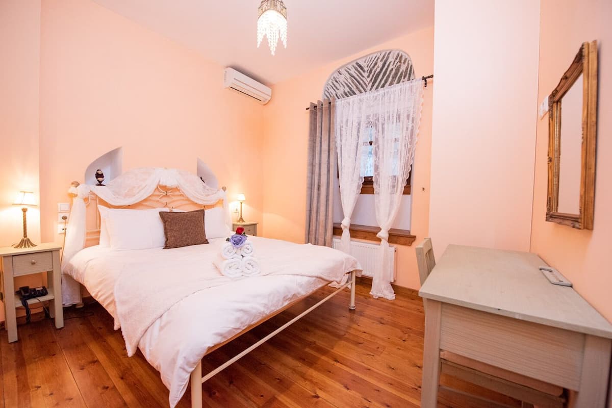 A bedroom with a bed, bedside tables, a desk, and a mirror.