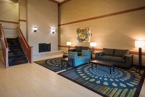 A hotel lobby with a staircase, seating area, and a fireplace. - Holiday Inn Express & Suites Chicago West-Roselle by IHG (Roselle)