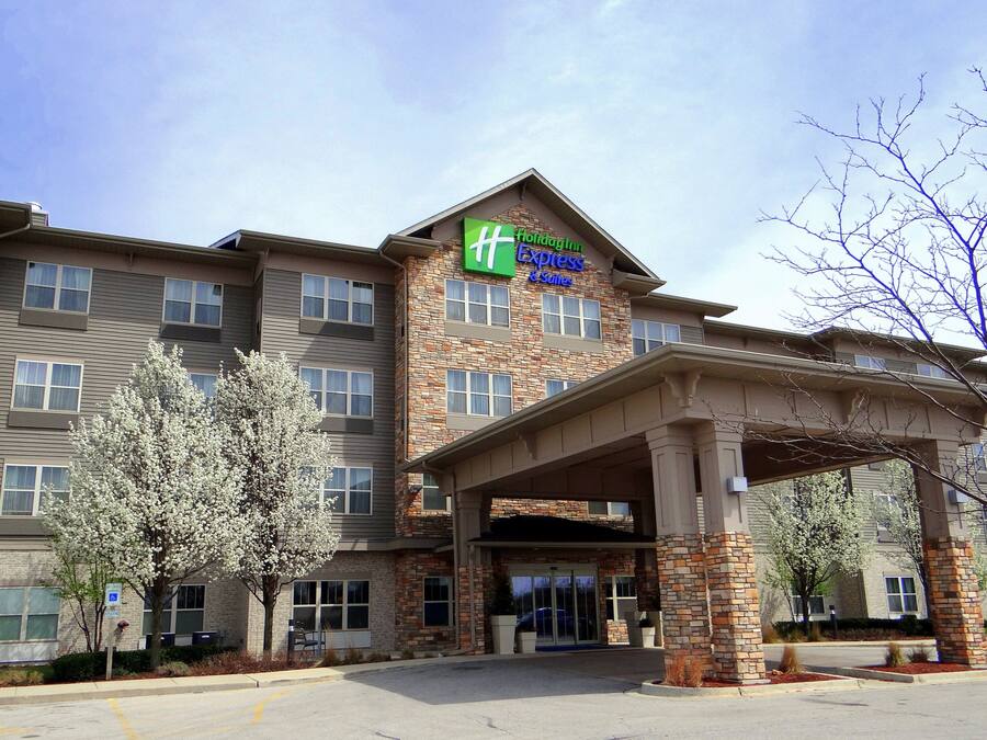 A Holiday Inn Express & Suites hotel with a stone facade, multiple windows, and a covered entrance.