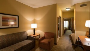 A hotel room with a sofa, armchair, desk, and lamps. - Holiday Inn Express & Suites Chicago West-Roselle by IHG (Roselle)