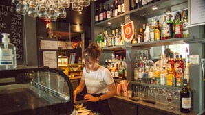 A bar area with shelves stocked with various liquor bottles, a bar counter, and a person working behind the bar. - Hotel Amager (Copenhagen)