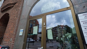 The entrance to Hotel Amager with a large arched glass door, a reception area, and a view of the street and buildings in the background. - Hotel Amager (Copenhagen)