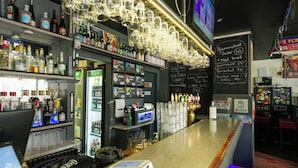 A bar area with shelves of liquor bottles, a cash register, and a chalkboard menu. - Hotel Amager (Copenhagen)