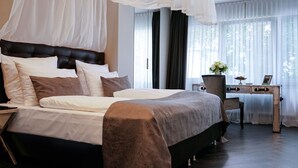 A bedroom with a large bed, a desk with a chair, and a window with sheer curtains. - Villahotel Rheinblick (Cologne)