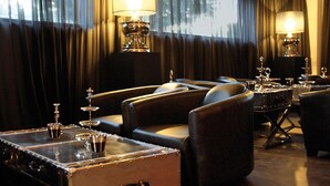 A room with leather sofas, a vintage trunk, and two wall-mounted lamps. - Villahotel Rheinblick (Cologne)
