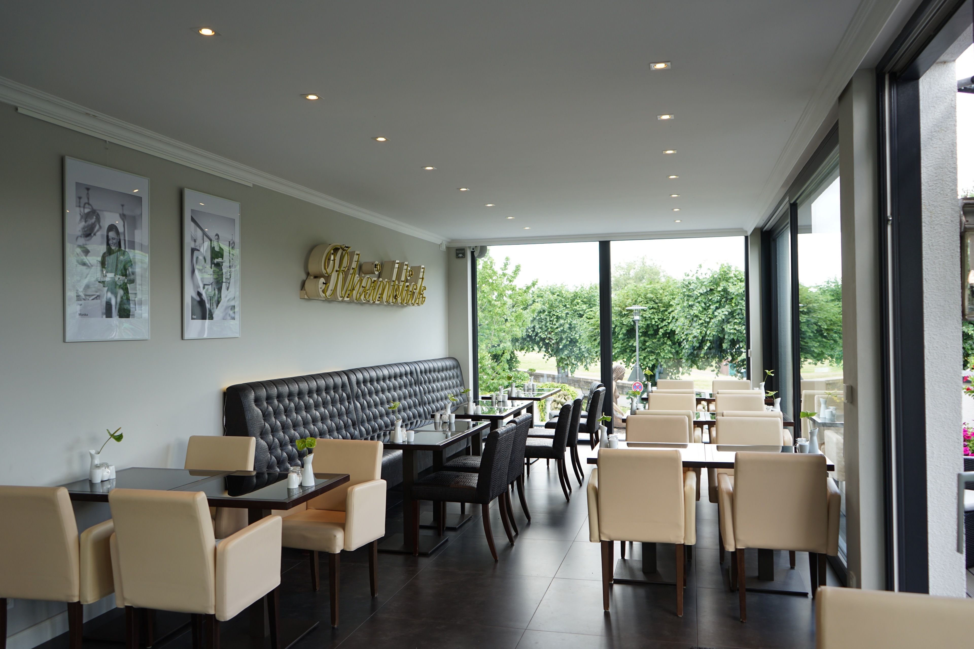 Ein modernes Restaurant mit einer schwarzen gepolsterten Bank, Esstischen und Stühlen.