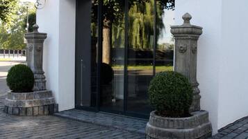 A modern building with a glass entrance, stone pillars, and a paved walkway.