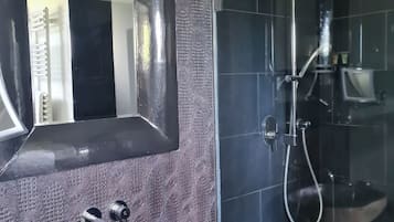 Un baño moderno con un espejo grande, un lavabo de piedra y una ducha con mampara de vidrio.
