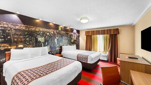 A hotel room with two beds, a desk, a chair, and a large window with curtains. - Rodeway Inn Capri (Little Ferry)