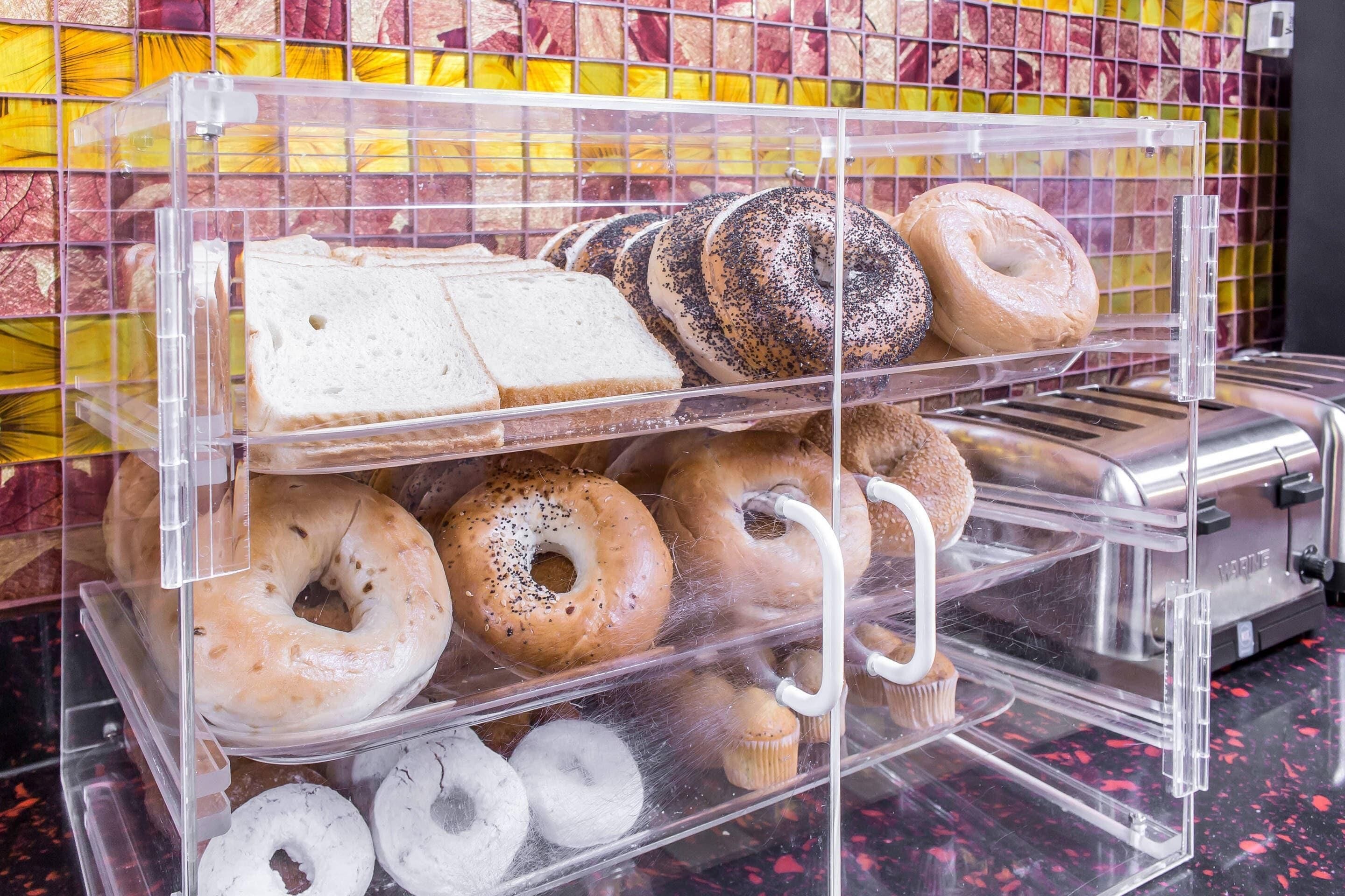 Vitrina de panadería con diversos productos horneados, incluyendo bagels, donas y pan.