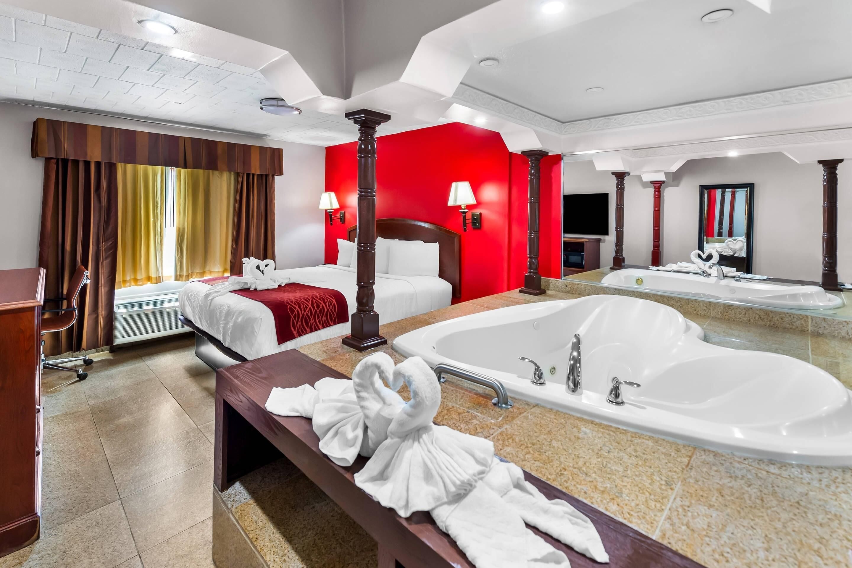 Habitación de hotel con una cama grande, una zona de estar, un lavamanos doble y un espejo amplio.
