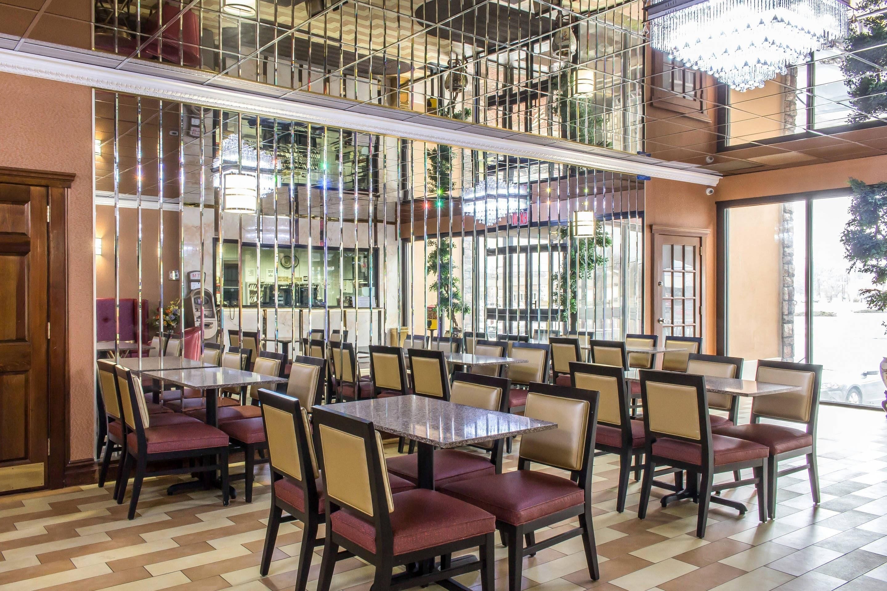 Een restaurant met meerdere eettafels en stoelen, een hoge plafond met glazen balustrade en uitzicht op de straat.