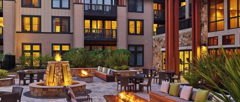 A multi-story hotel with outdoor seating areas featuring fire pits and comfortable seating.
