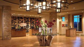A lobby with a wooden floor, a glass-top table with vases, and a wall with wine bottles. - The Westin Verasa Napa (Napa)