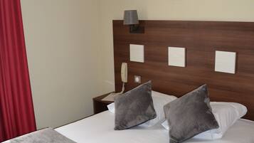 A hotel room with a bed, a nightstand, a lamp, and a painting on the wall.
