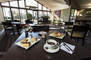 A dining area with tables set for breakfast, including croissants, pastries, and coffee.