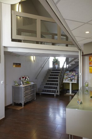 A reception area with a staircase leading to a second floor, a reception desk, and a bulletin board with posted items.