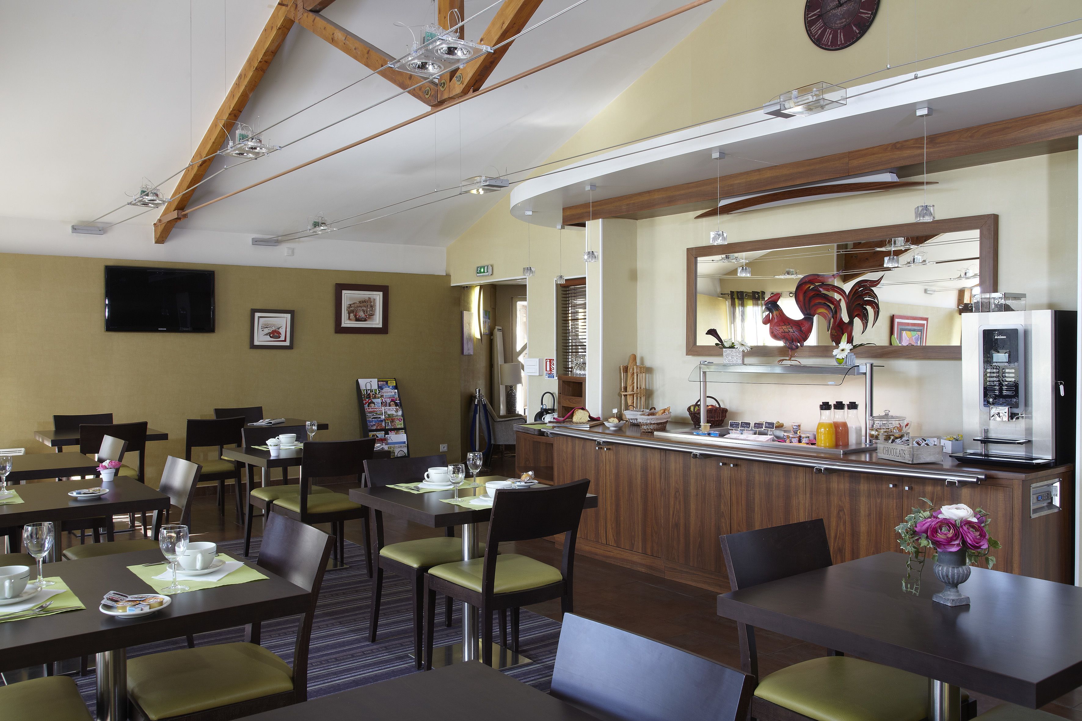 Un comedor de hotel con mesas, sillas, una barra de cocina y un reloj en la pared.