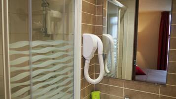 A bathroom with a glass shower enclosure, a white sink, and a mirror above it.