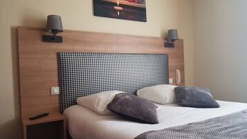 Una camera d'albergo con una testiera a motivi a zig-zag di caccia, un comodino con un telecomando e due lampade a parete.