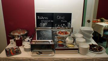 Disposição de buffet com seções identificadas para ovos mexidos e frutas.