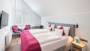 Una habitación de hotel moderna con una cama grande, un escritorio y una silla.