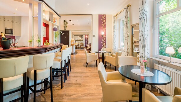 Un hall de hotel con zona de bar, arreglos de asientos y vistas al exterior.