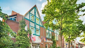 Un hotel de estilo europeo tradicional con una entrada destacada, varias banderas y fachada de ladrillo.