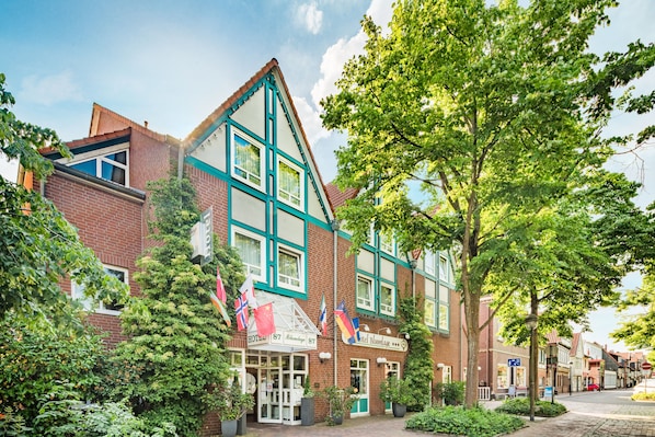 A traditional European-style hotel with a prominent entrance, multiple flags, and a brick facade. - Hotel Blumlage Celle (Celle)