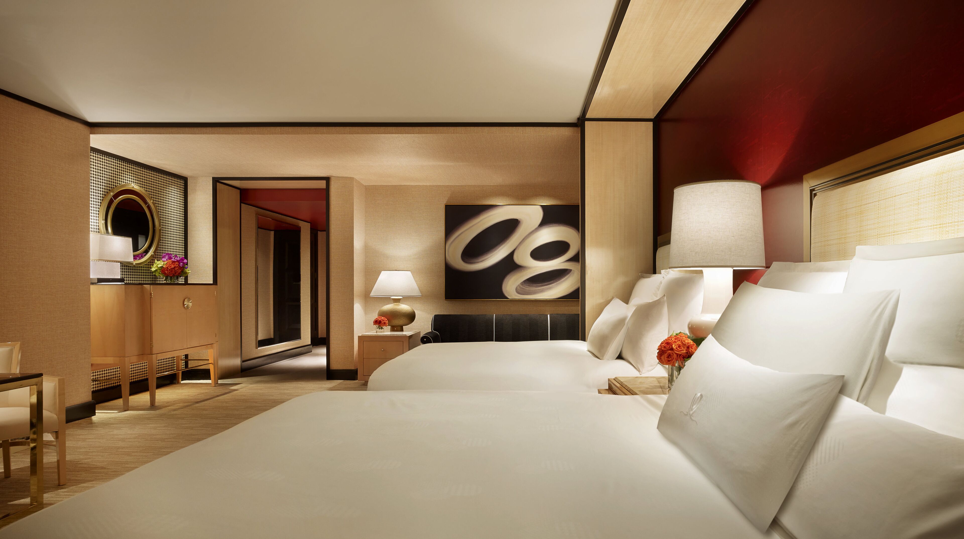 A hotel room with a large bed, a nightstand with a lamp, a mirror, and a wall art piece.