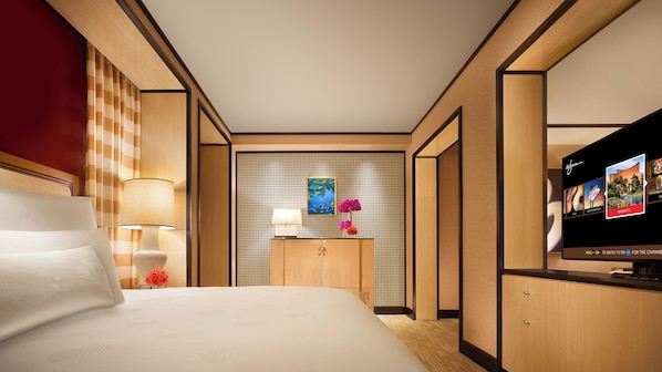Habitación de hotel con cama, televisión, un cuadro en la pared y un panel decorativo.