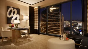 A modern hotel room with a large window offering a view of a cityscape at night.