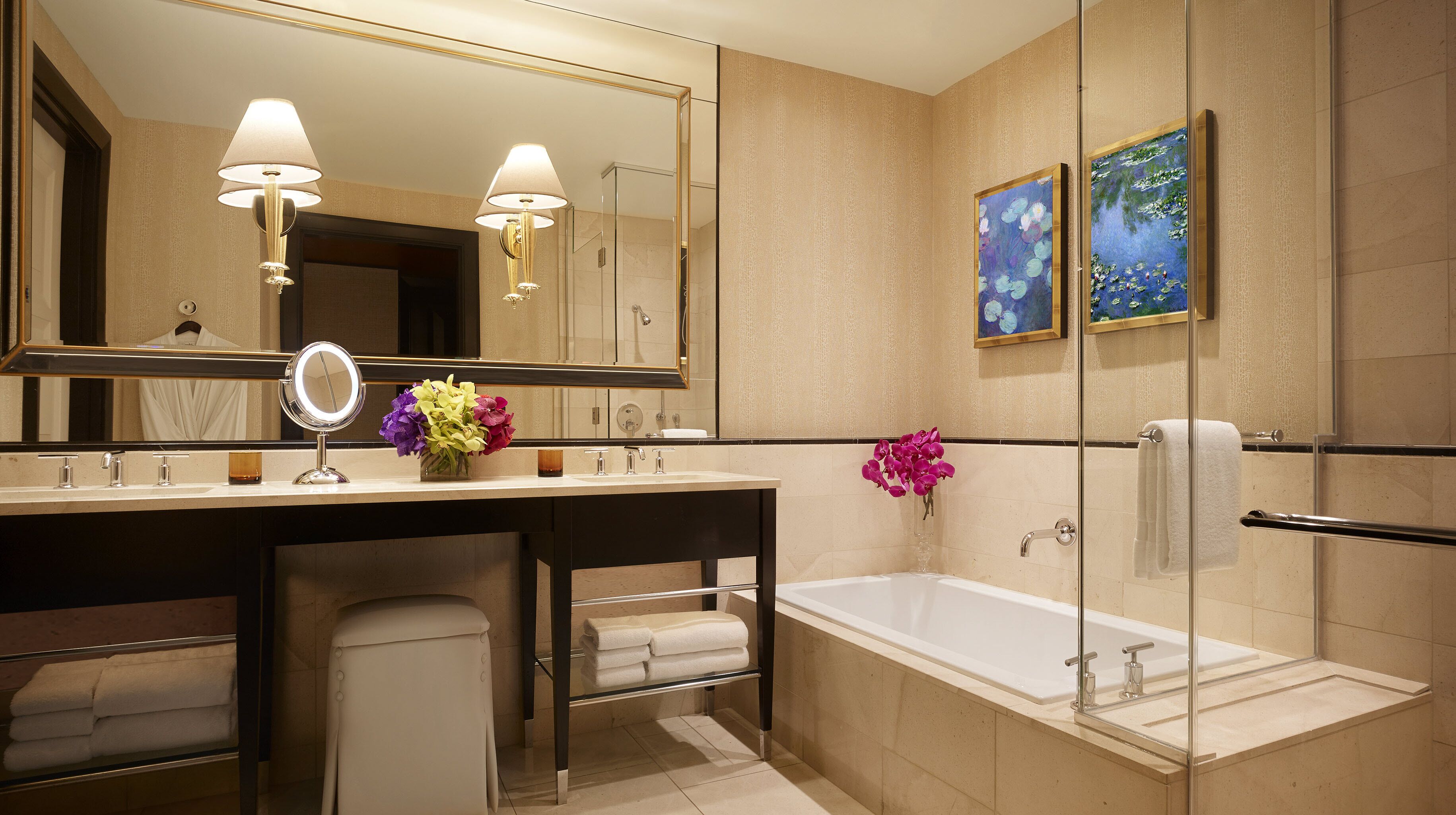 Un baño moderno con un espejo grande, dos lavamanos, una bañera y una cabina de ducha con mampara de vidrio.