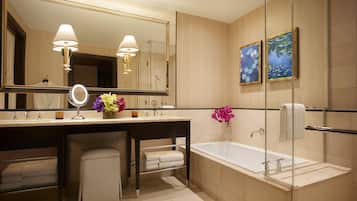 Un baño moderno con un espejo grande, dos lavamanos, una bañera y una cabina de ducha con mampara de vidrio.