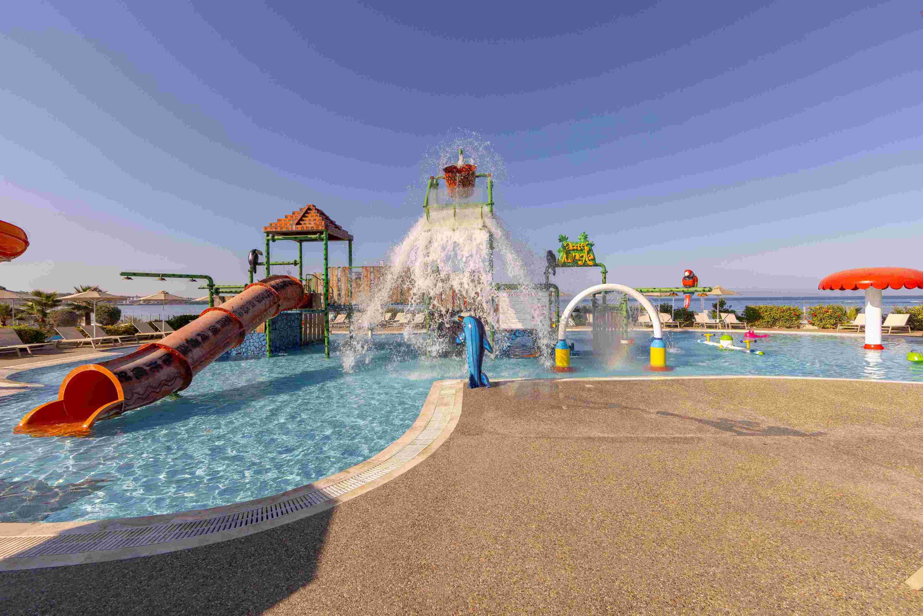 A water park with a large slide, a water fountain, and a pool area.
