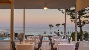 Un restaurante con mesas dispuestas para comer, con vistas a una piscina y al mar.