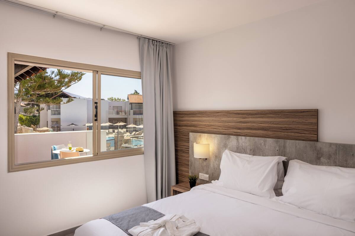A hotel room with a large bed, a view of the pool area, and a modern design.