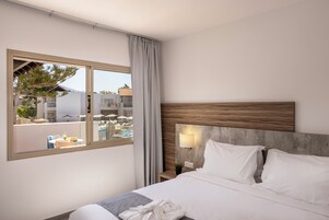 Habitación de hotel con una cama grande, vistas al área de la piscina y un diseño moderno.