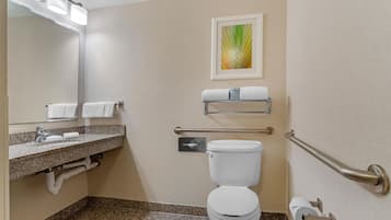 A modern bathroom with a toilet, sink, and handrails.