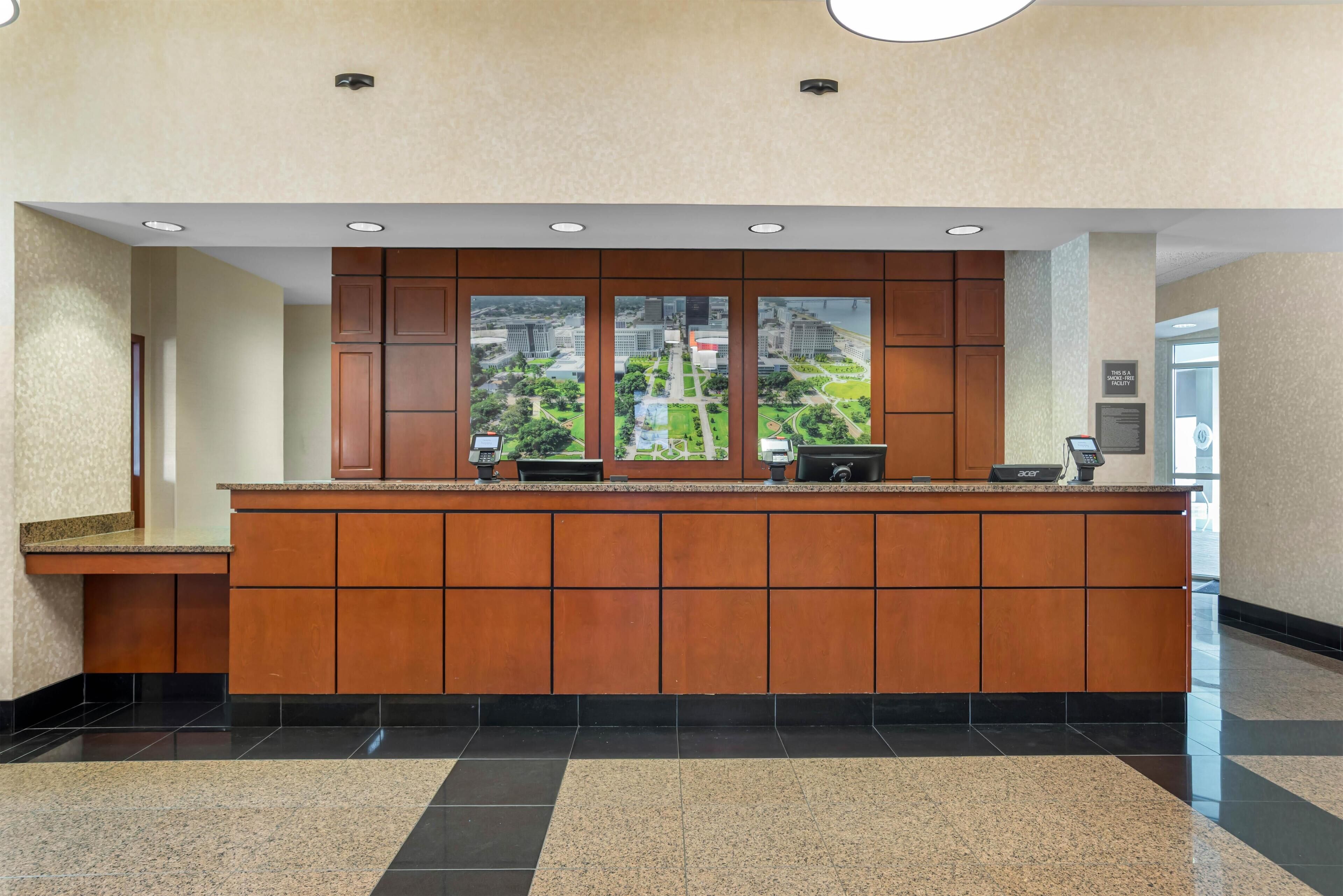 A reception desk with a view of a park and buildings through large windows.