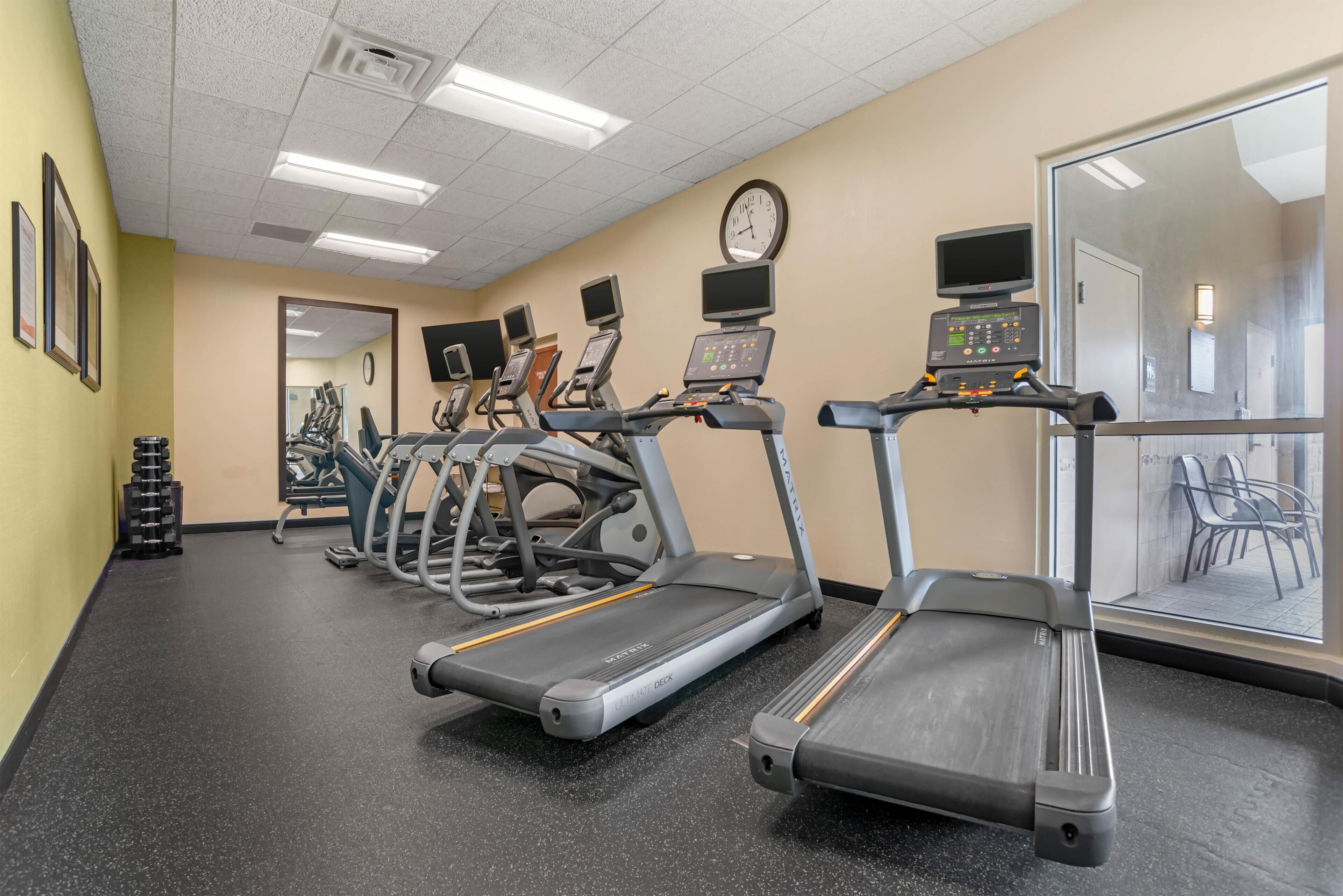 Centro de fitness com esteiras, bicicletas ergométricas e espelho.