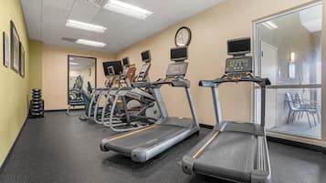 Centro de fitness com esteiras, bicicletas ergométricas e espelho.
